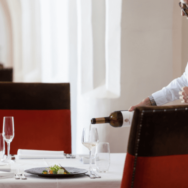 waiter pouring a glass of wine at divinus restaurant in evora 